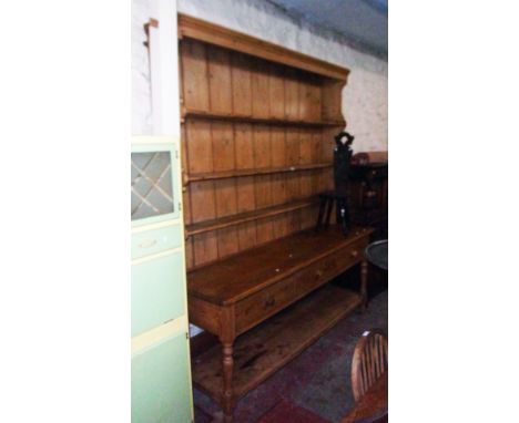 A 6' 8" 19th Century waxed pine two part dresser with moulded cornice and shaped sides to the three shelf open plate rack top