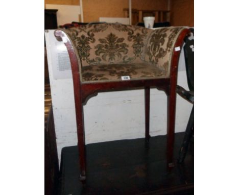 An early 20th Century stained mahogany framed scroll arm dressing chair with repeat pattern tapestry upholstery, set on mould