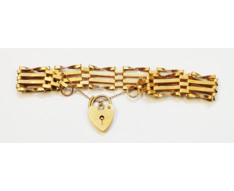 A yellow metal four bar gate-link bracelet with hallmarked 375 gold heart shaped padlock