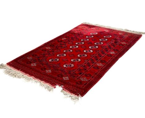 A Bokara Rug with two rows of white medallions on a red ground (torn) 200cm x 120cm 