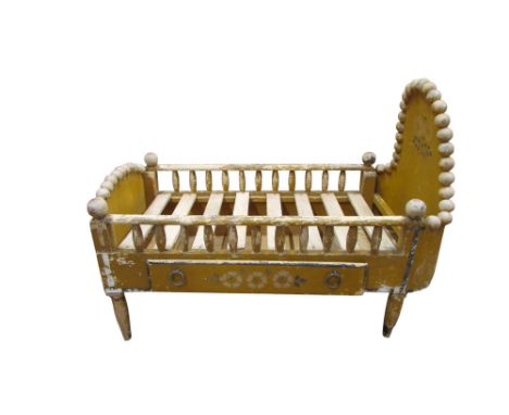 A small decorative early 20th century painted pine folk art cot, fitted with single drawer, with bobbin borders and turned sp