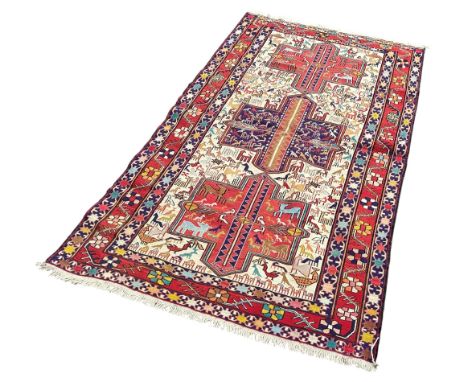 A hand knotted flat weave rug decorated with stylised animals with floral boarders, 200cm x 110cm