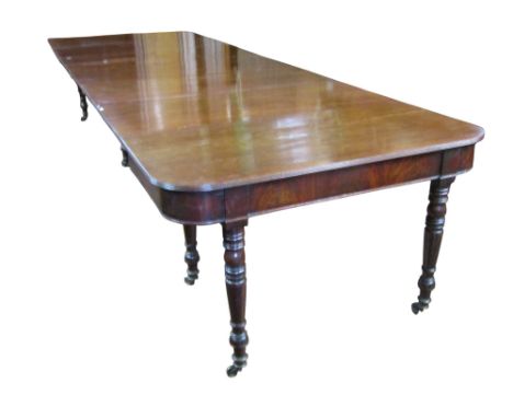 A Georgian mahogany extending dining table with concertina action, raised on eight turned supports, enclosing five additional
