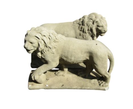 A pair of cast composition stone garden terrace ornaments in the form of standing lions set on rectangular platform bases, 56