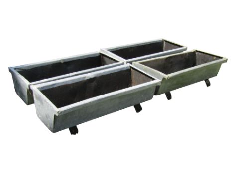 A set of four weathered galvanised planters of rectangular tapered form raised on wooden sledge feet, 19 cm high x 62 cm x 27