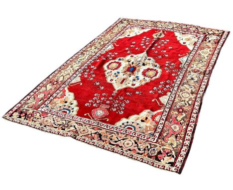 A Shirvan rug with a central floral medallion on a red ground interspersed with flowers, 180cm x 147cm