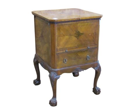 A walnut veneered freestanding drinks cabinet, with twin hinged lid, over a  slide and frieze drawer, raised on claw and ball