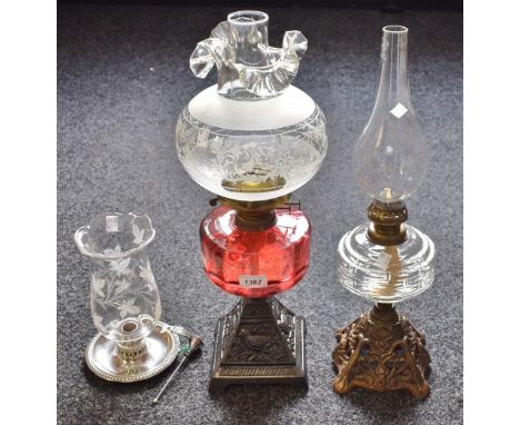 A cast iron oil lamp, cranberry glass resevoir; another; chamber stick (3)