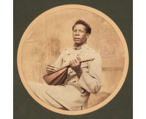 * Africa. Portrait of an African man in French army uniform playing a lute, c. 1890, circular albumen print, colour tinting, 