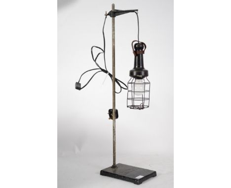 A vintage 20th century inspection lamp complete with wire cage raised on a cast metal base having lettering for Phillip Harri
