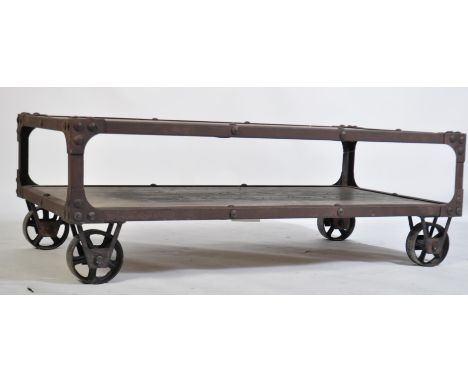 A vintage industrial style cart coffee table, having limed top and lower oak tiers with an iron studded frame raised on vinta