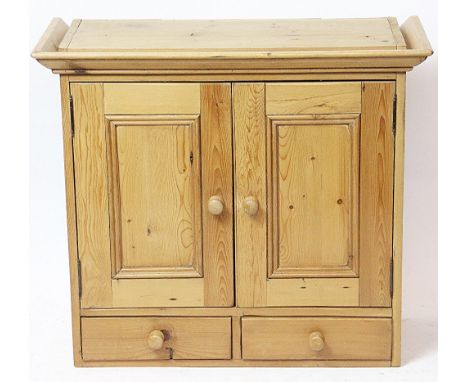 A pine hanging wall cabinet, the two panelled cupboard doors enclosing a fitted shelf above two short drawers, 71cm H x 80cm 