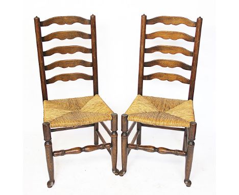A set of six oak ladder back chairs, with rush seats, on turned legs