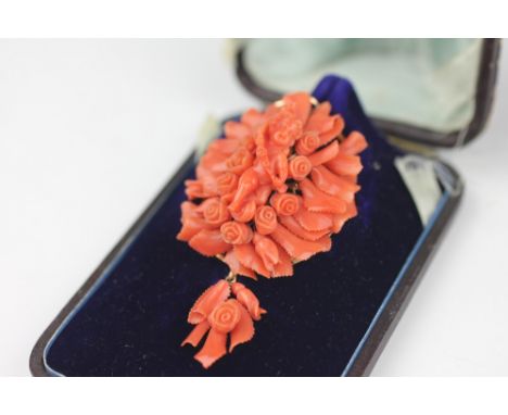 A Victorian Italian carved coral brooch, the oval form brooch with central cherub and floral and foliate surround suspending 