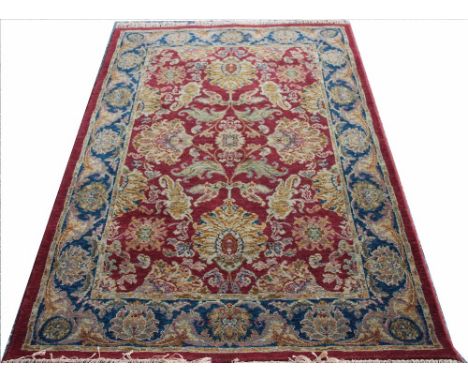 A Royal Agra wool carpet, floral spurs against a red ground with blue border, fringed, 177cm x 121cm 