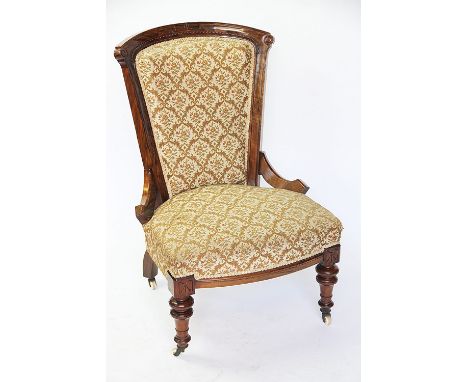 A walnut nursing chair with fret work carved detail, scroll support and upholstered back and seat on turned legs and ceramic 