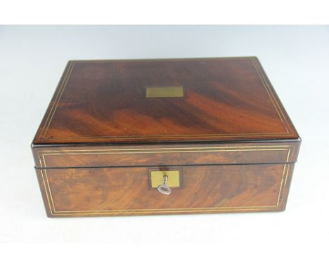An Edwardian walnut and brass inlaid writing slope, the hinged cover with inset brass plaque enclosing a compartmented interi