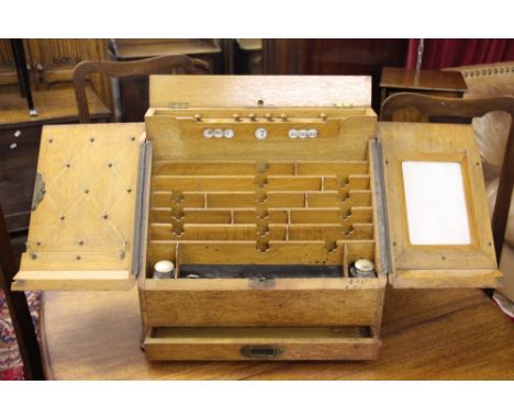 A Victorian golden oak stationary box, the two hinged doors enclosing a compartmented interior with perpetual day date displa