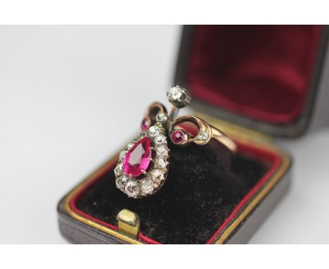 A SYNTHETIC ruby and diamond set dress ring, the pear shaped untested ruby within a surround of old cut diamonds and scroll c