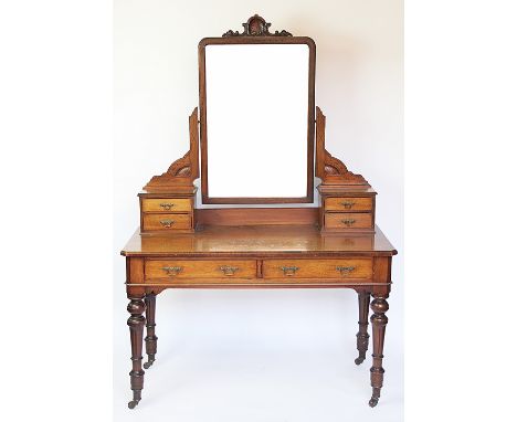 A Victorian mahogany dressing table in aesthetic style, the central mirror surmounted with shell, flanked by two short drawer