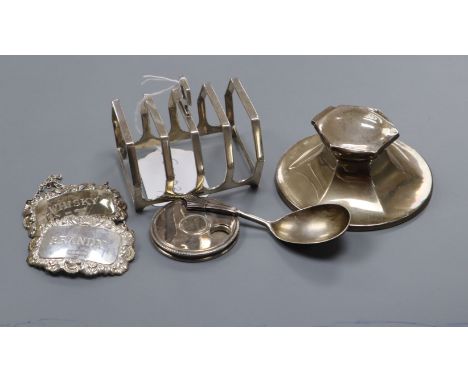 A George V silver capstan inkwell, an Art Deco toastrack, a pair of decanter labels, a plated caddy spoon and a plated pill d