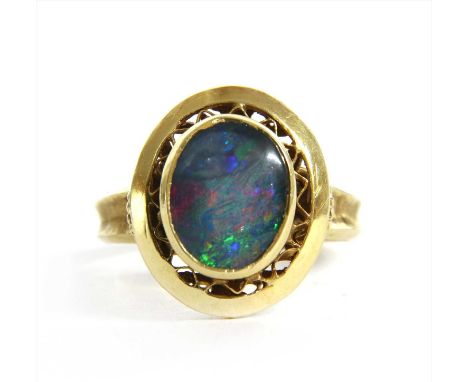 A gold opal triplet ring, with an oval opal triplet, rub set to openwork surround, concave shoulders and a plain shank, marke