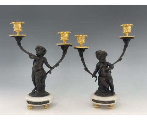 A pair of French bronze double branch candelabra, late 19th Century, in the form of cherubs, gilt metal sconces and bobeches,