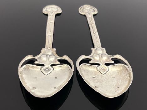 A pair of Arts and Crafts silver spoons, TW, Birmingham 1901, the planished spade bowls on open tendril brackets and relief m