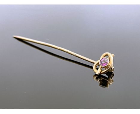 A 9 carat gold and pink gem set stick pin, the knotted wire head set with a facet cut stone, 5.5cm long, 1.4g