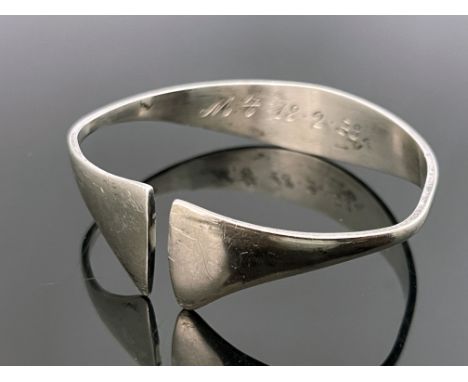A Modernist silver bangle, circa 1972, stylised torque form with axe head ends, 6.5cm wide, 0.92ozt