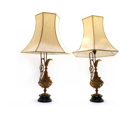 A pair of Continental gilt metal table lamps, 20th century, in the form of ewers, each on ring turned ebonised base, each wit