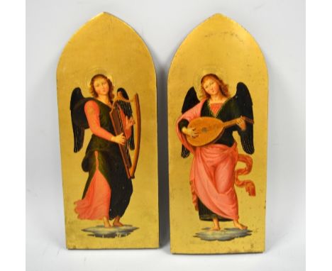 A PAIR OF GODWIN STYLE GOTHIC PANELS, with winged angels playing harp and flute, atop clouds to gilt background, the arched p