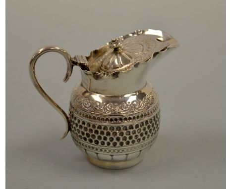 A SILVER LIDDED JUG, with beaten central band over scalloped base to circular foot and scrollwork over, urn finial to hinged 