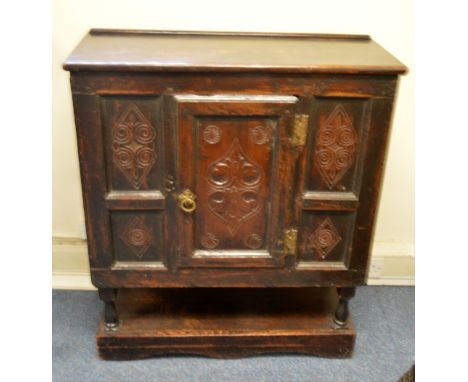 A RUSTIC OAK CABINET, with carved detail to front panels, central door to shelved interior over stretcher shelf bracket balus