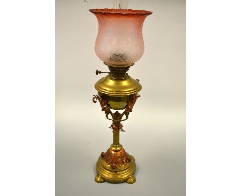 A BRASS OIL LAMP, with upper leafage mounts with turned column support and central finial under brass reservoir with opaque a