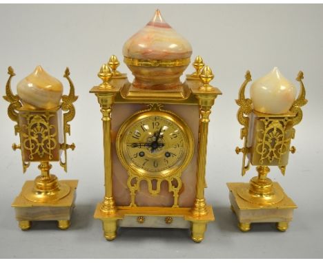 AN ONYX CLOCK GARNITURE, of Eastern influence, the clock of temple form with dome top, pilaster supports with finials, ormolu