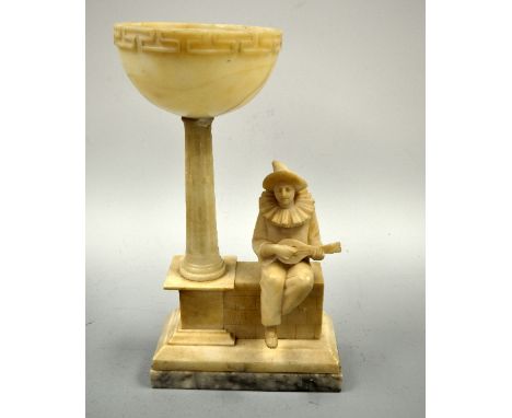 AN ALABASTER LAMP, modelled as seated Pierrot playing mandolin on wall with column support to shade on plinth base, approxima