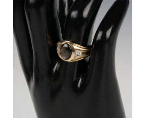 This stunning ring features an oval black star sapphire center stone with a small diamond on either side. Marked 14k inside t