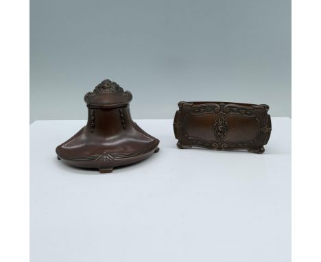 A bronze inkwell designed with floral patterns, featuring a flap that opens into a blue glass well accompanied by an ink blot