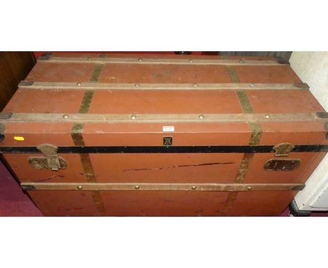 An early 20th century painted metal and wood bound hinge top travelling trunk, with iron end carry handles, width 100cm