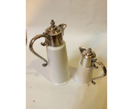 A pair of silver plated candle sticks and two ceramic and plated jugs.