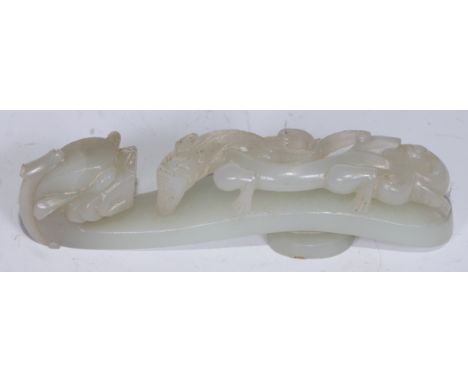 A Chinese pale celadon/white jade belt hook, late Qing dynasty, of typical serpentine form, carved and pierced with chilong c