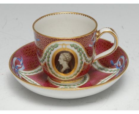 A Chelsea Derby teacup and saucer, painted in monochrome with gilt oval portrait cartouches, blue  ribbon tied green  husks, 