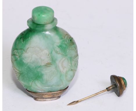 A Chinese flattened oval greenish/white jadeite snuff bottle, carved in relief with flowers, silver coloured metal base, circ