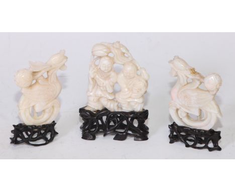 A Chinese carved opal garniture, the central group with two figures standing holding flowering stems, flanked by oversized ve