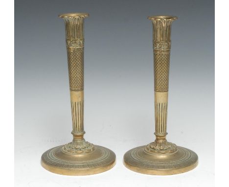 A pair of French Empire gilt brass table candlesticks, lotus sconces and socles, engine turned borders, 26cm high, c.1830 