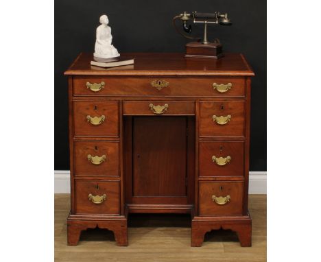 A 19th century mahogany kneehole desk, three-quarter crossbanded rectangular top above an arrangement of drawers, brass swing