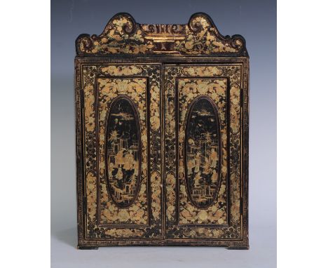 An early 19th century Chinese export lacquer table cabinet, shaped scroll pediment above a pair of doors enclosing five drawe