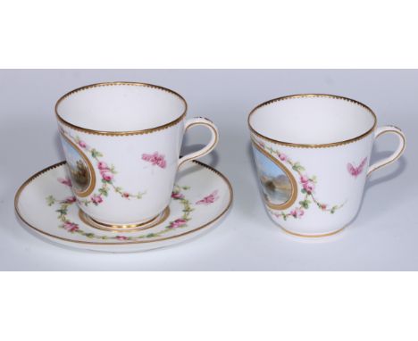 A pair of Minton  coffee cups and a saucer, painted with two landscapes in raised gilt panels surrounded by roses and butterf