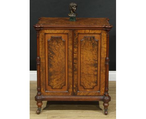 A Victorian walnut enclosed bookcase, of small and neat proportions, hipped rectangular top above a pair of panel doors enclo